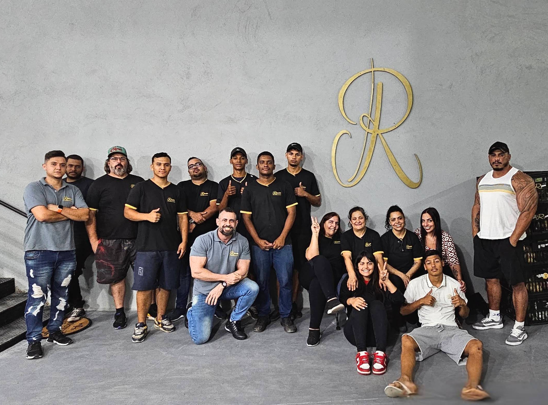 Equipe da Rizzullin reunida diante da marca da empresa
